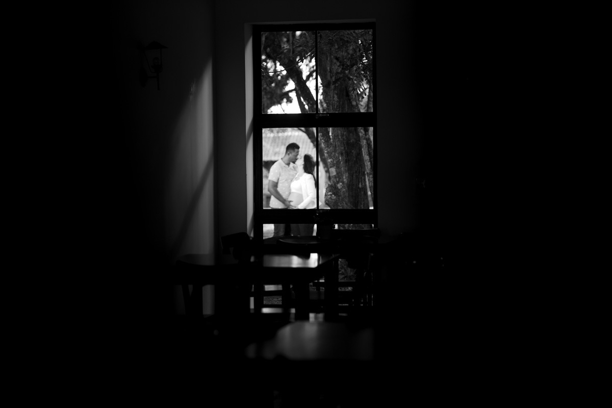 book de gestante com foto em preto e branco com casal aparecendo numa janela