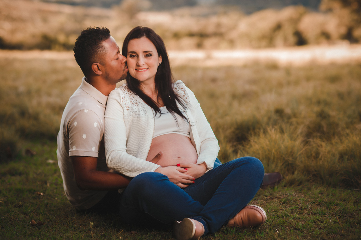 book de gestante com casal sentado um do lado do outro e esposo dando beijo na esposa