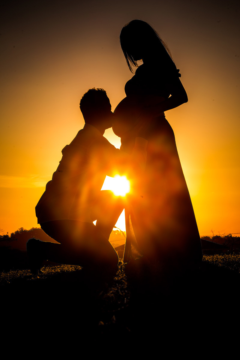 book de gestante com fotografia do esposo beijando a barriga com fotografia em silhueta