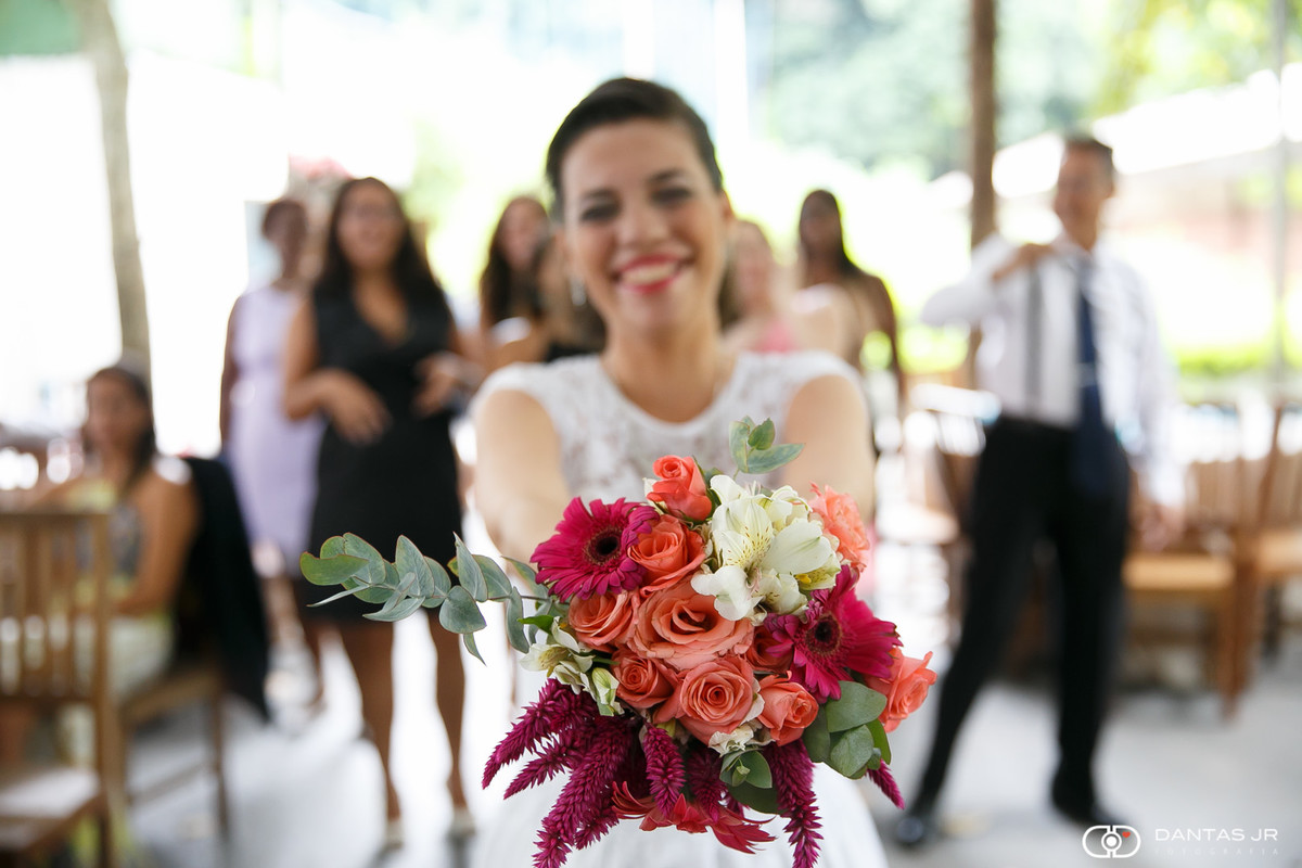 Noiva apontando bouquet para câmera antes de joga-lo para as convidadas durante casamento ao ar livre por Dantas Jr. Fotografia