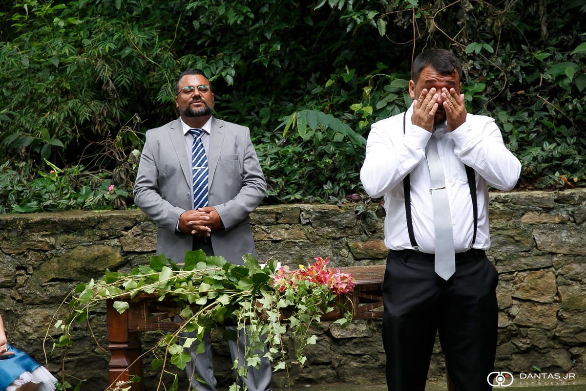 Noivo chorando emocionado no altar enquanto noiva entra na cerimônia de casamento ao ar livre por Dantas Jr.