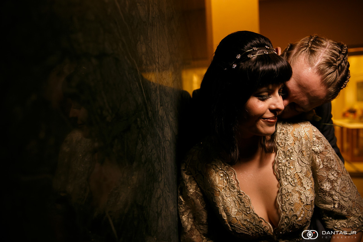 Casal de noivos namorando em ensaio pós cerimônia com reflexo na parede por Dantas Jr.