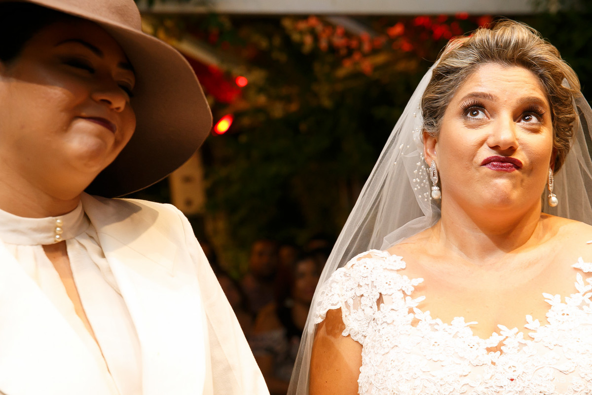 Casal de mulheres lésbicas em casamento homoafetivo no altar rindo e fazendo caretas por Dantas Jr. Fotografia