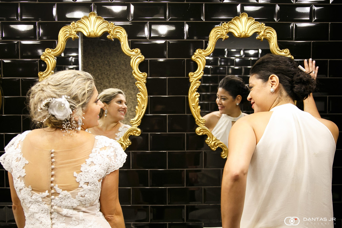 Casal de mulheres noivas lésbicas no banheiro se olhando pelo espelho em casamento homoafetivo no Bistrô 160 por Dantas Jr.