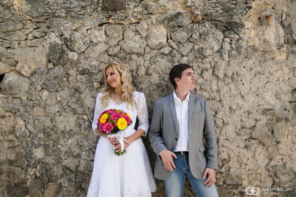 Casal de noivos olhando para lados opostos em parede de pedras após casamento no centro do RJ por Dantas Jr. Fotografia