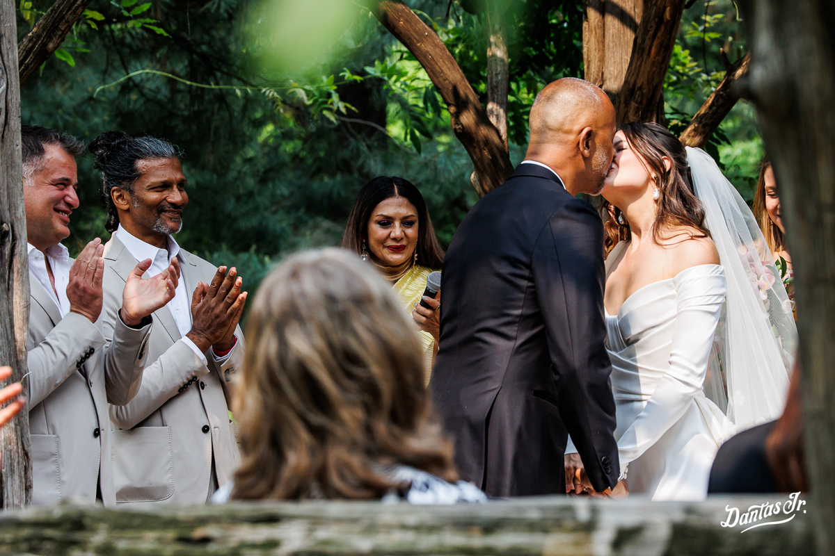 Beijo dos noivos sendo aplaudidos por padrinhos em cerimonia de casamento no Cop Cot Central Park em NYC por Dantas Jr.