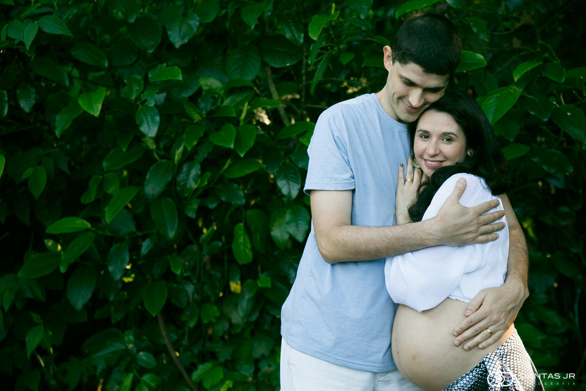 casal com mulher gravida namorando em muro de plantas