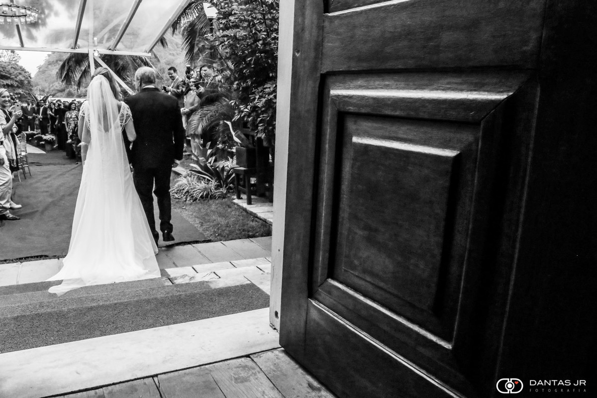 Noiva entrando na cerimônia acompanhada do pai no solar das palmeiras na ilha da gigoia no RJ em cerimonia ao ar livre de dia casamento judaico por dantas jr