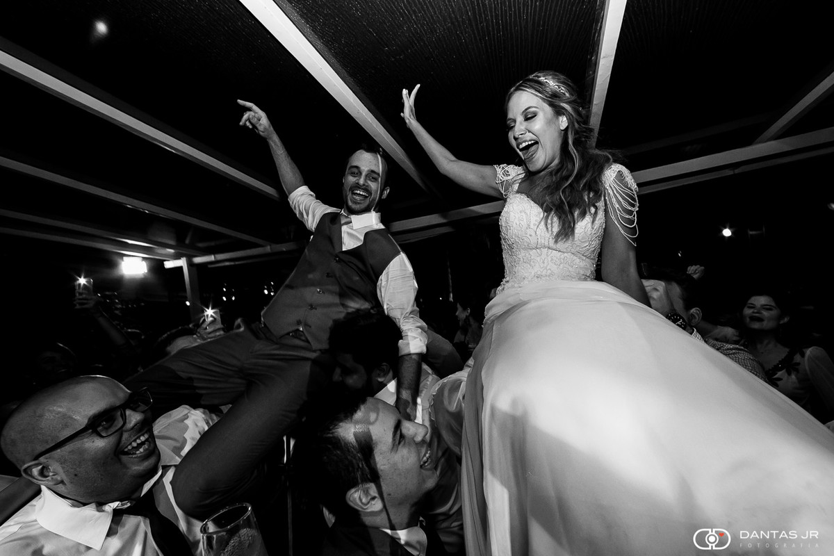 Casal de noivos em cerimônia judaica na ilha da gigoia sendo levantados em cadeiras na pista de dança por Dantas Jr