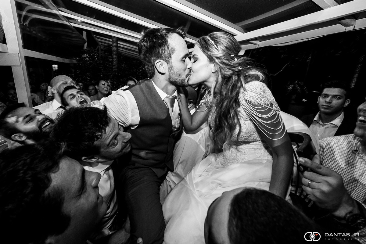 Casal de noivos em cerimônia judaica na ilha da gigoia se beijando e sendo levantados em cadeiras na pista de dança por Dantas Jr