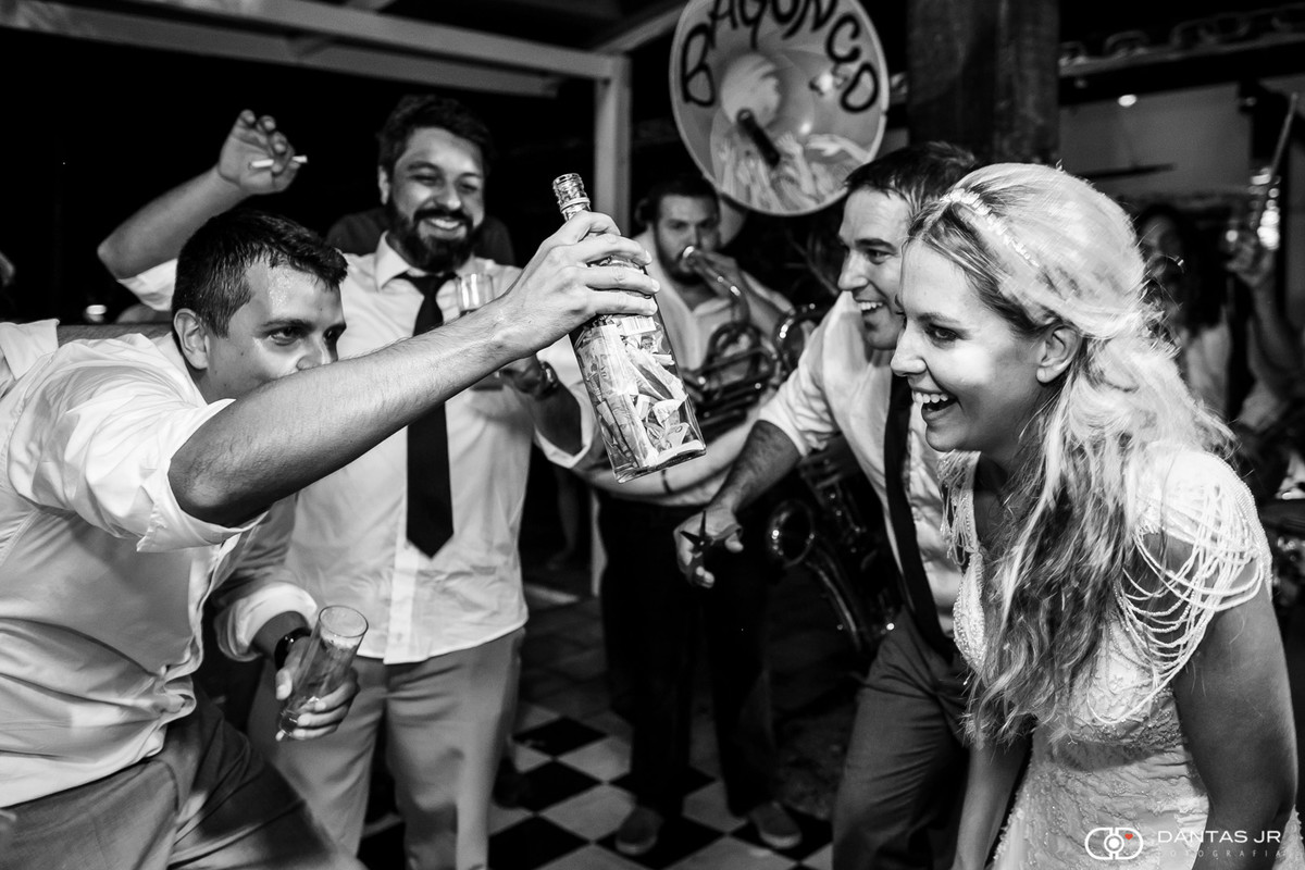 Padrinho entregando garrafa com dinheiro enquanto Casal de noivos dançam animados na pista de dança por Dantas Jr