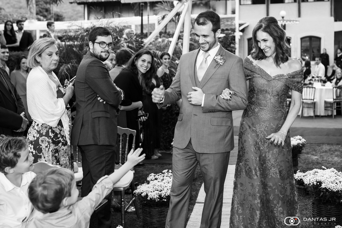 Noivo caminhando e cumprimentando criança em cerimônia ao ar livre de dia no solar das palmeiras na ilha da gigoia no RDJantas Jr.