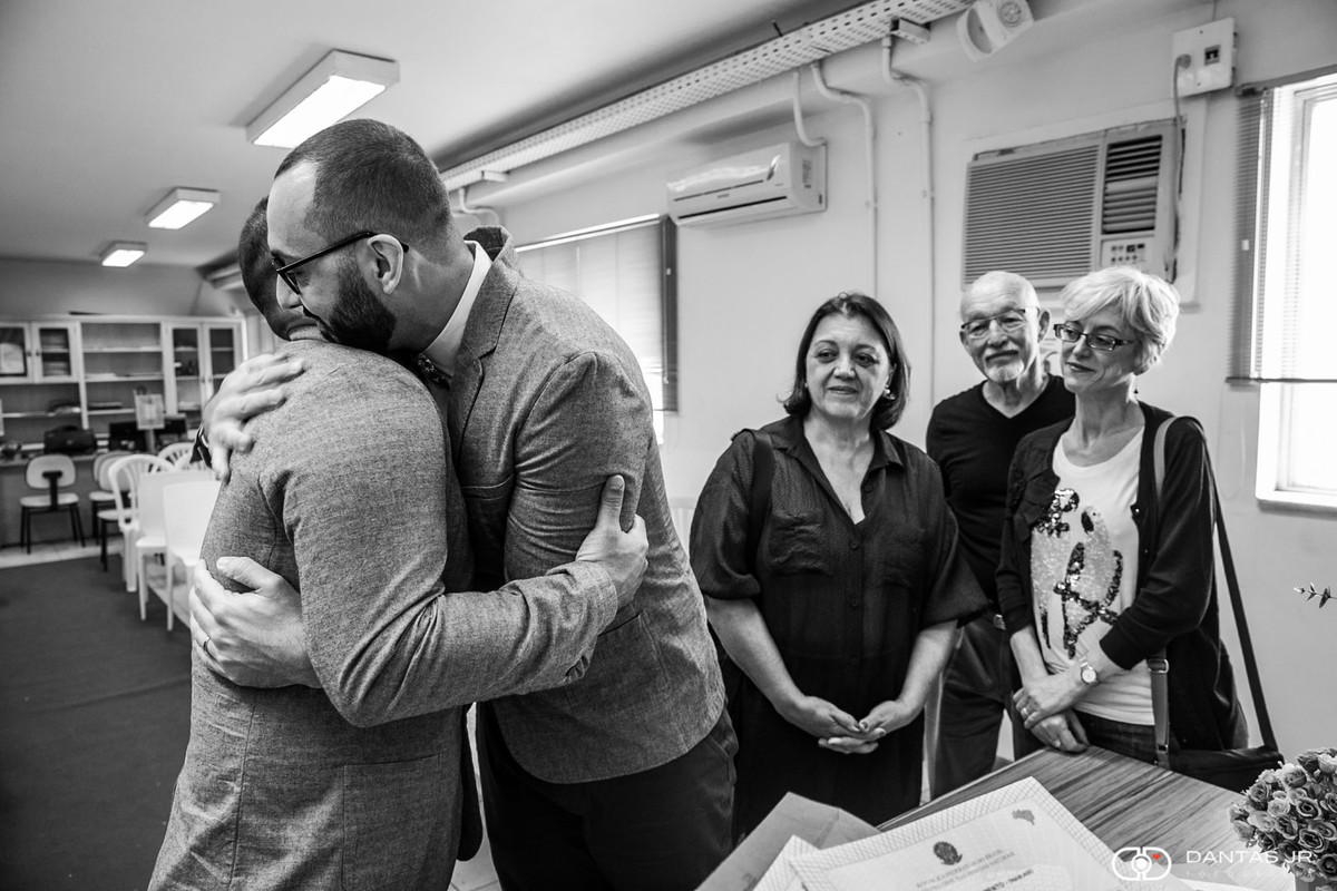 casal gay se abraçando sob olhares de testemunhas em cartorio Botafogo para casamento homoafetivo