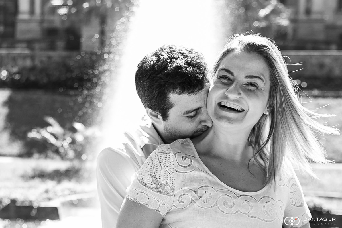 Casal de namorados com noivo beijado pescoço da noiva em frente a chafariz no Parque Lage no RJ por Dantas Jr.