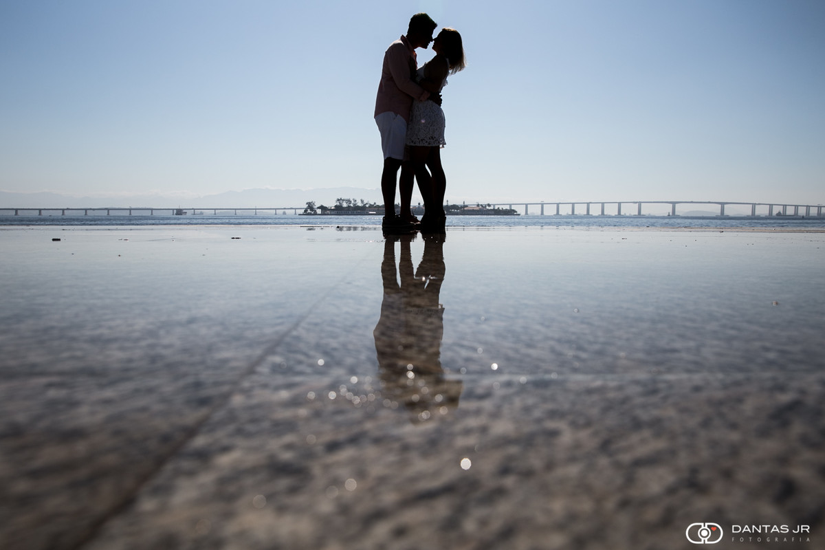 Casal de namorados se beijando com silhueta refletida em poça de agua e com a ponde rio niteroi ao fundo em zona portuaria no Boulevard Olimpico no RJ por Dantas Jr Fotografia