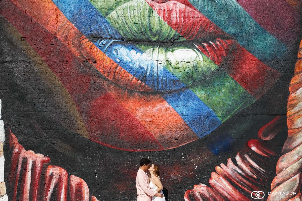 casal namorando em ensaio prewedding se olhando e rindo em frente a painel do kobra no boulevard olimpico no RJ por Dantas Jr Fotografia