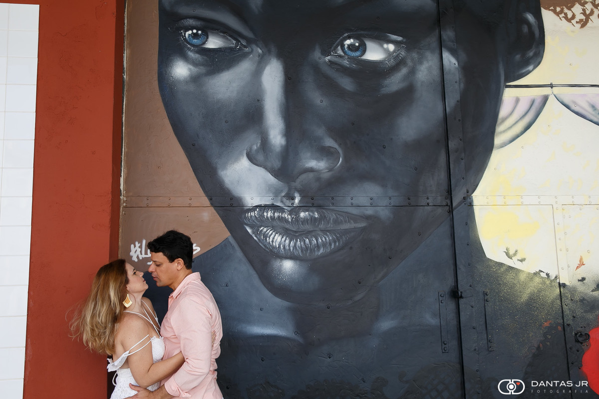 casal de noivos namorando durante ensaio pre wedding com pintura de negra olhando eles em ensaio pre wedding no Boulevard Olimpico no RJ por Dantas Jr Fotografia