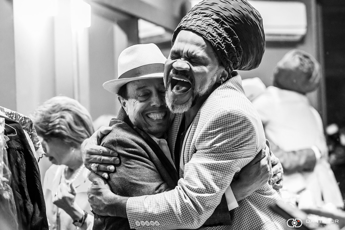 sergio mendes recebe carlinhos brown no camarim do blue note rio e os dois se abraçam felizes por Dantas Jr.