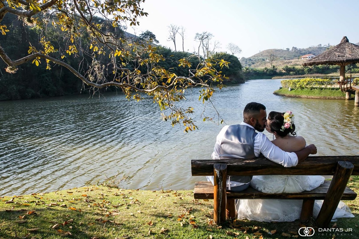 casal namorando em banco em frente a lago de fazenda com gramado em ensaio Trash the Dress por Dantas Jr. Fotografia