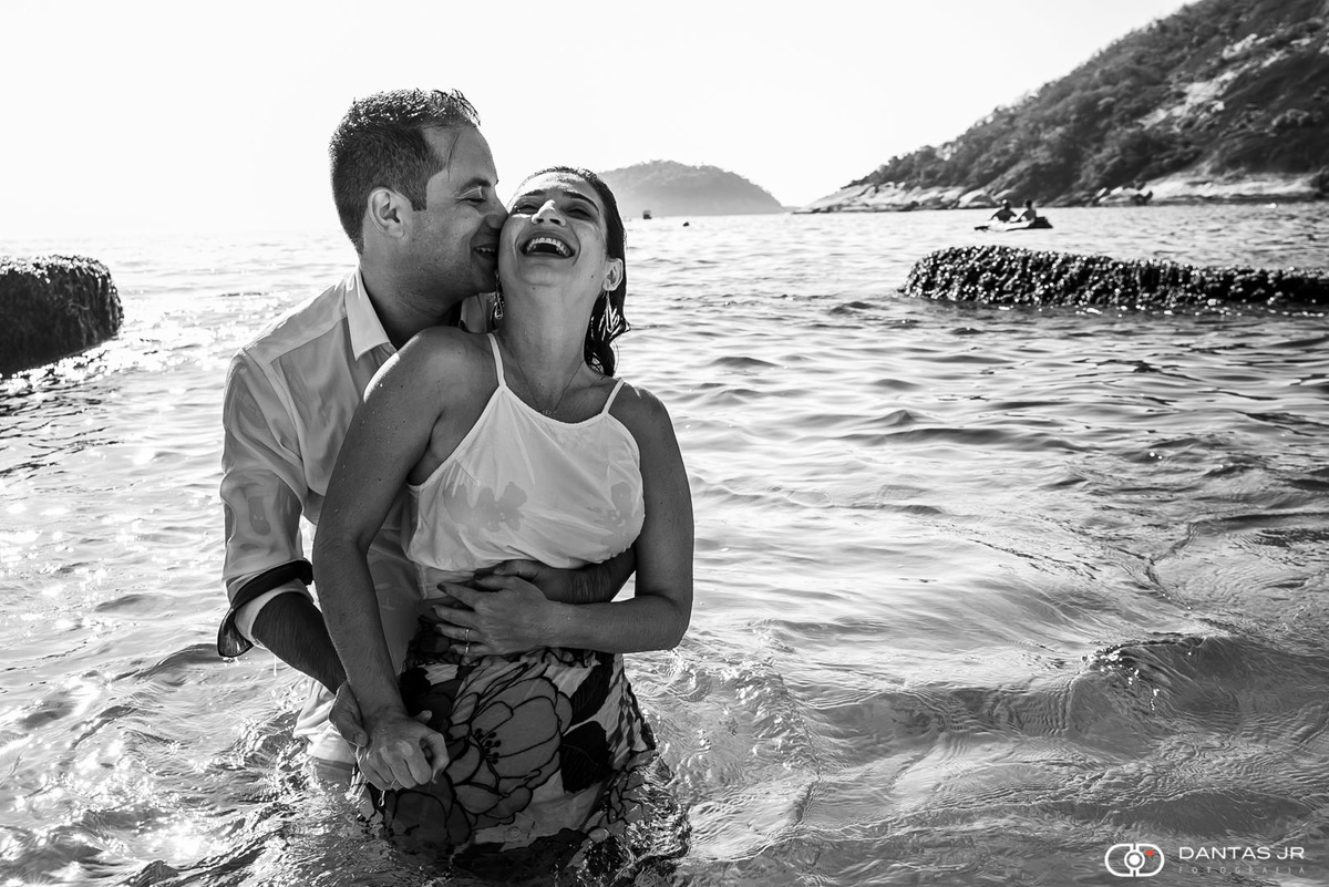 casal namorando dentro da água do mar molhados e rindo apaixonados em ensaio prewedding