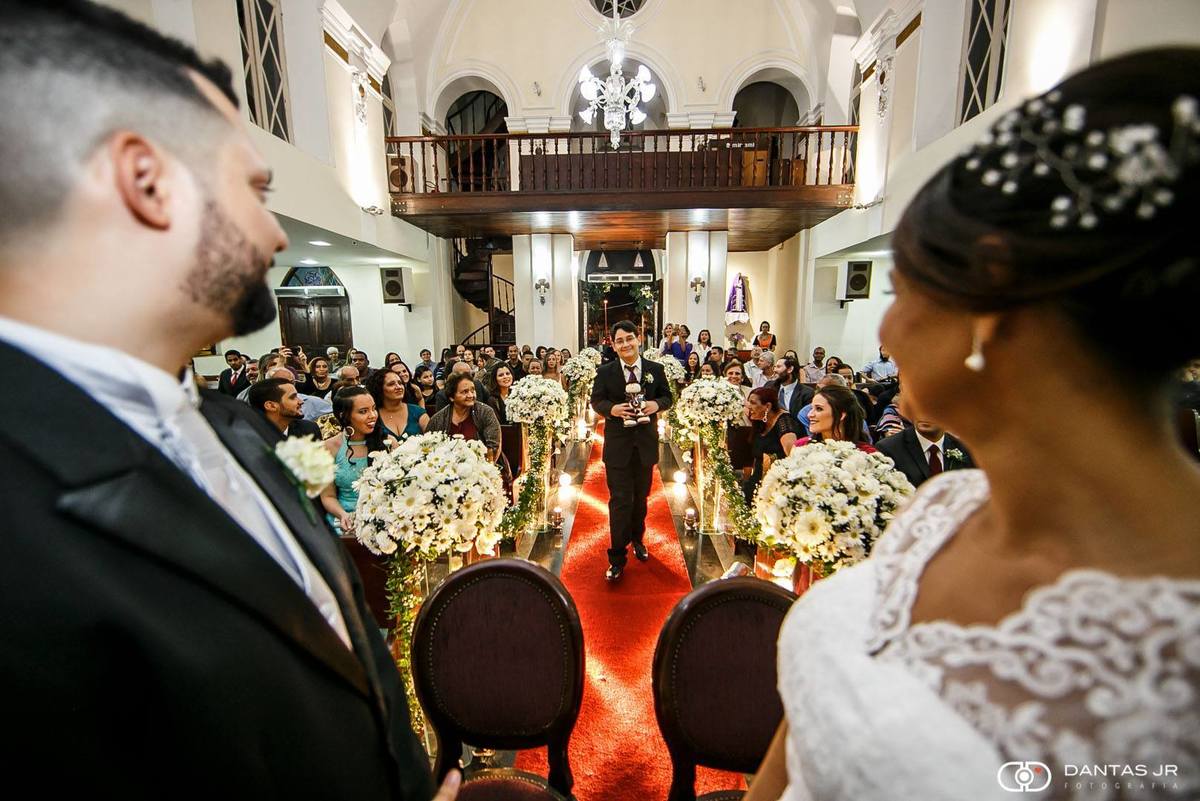 noivos em igreja durante casamento olhando entrada do filho com imagem de santo