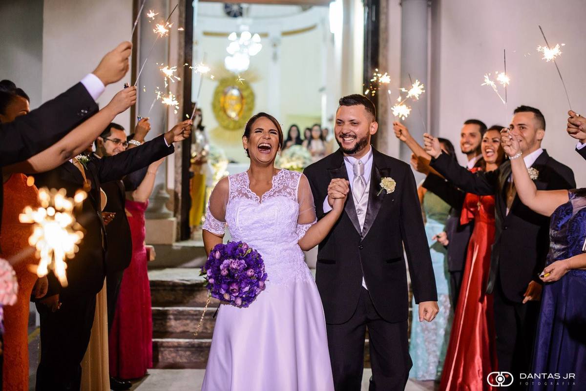 noivos saindo da igreja com padrinhos balançando os sparkles