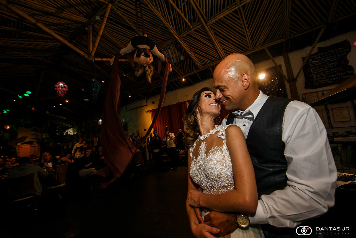 casal de noivos se beijando enquanto artista de circo faz performance com lenços no fundo no Tantra Mongolian Grill