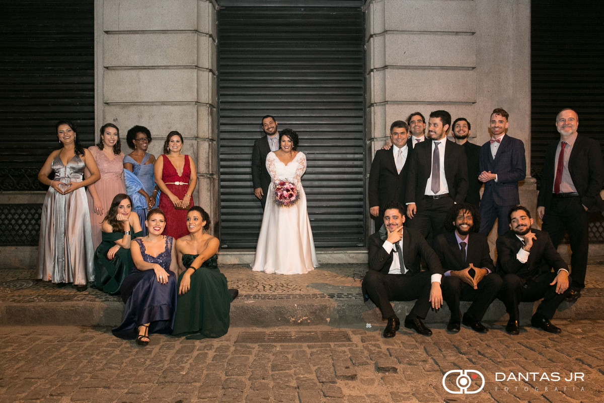 noivos e padrinhos posando para fotografia após o casamento reazliado no meio da rua