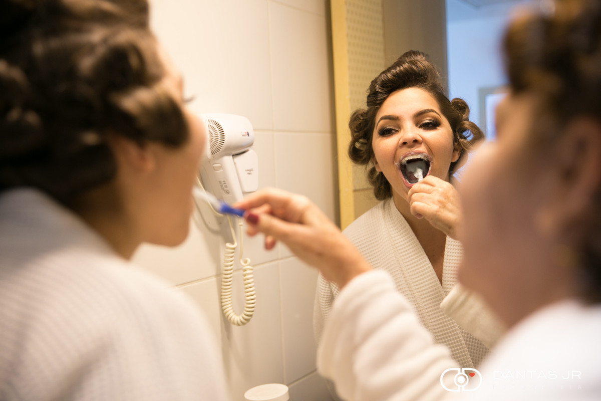 mãe escovando a língua e os dentes da noiva no making of