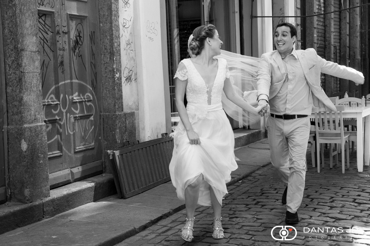 casal de noivos correndo felizes em ensaio trash the dress pelas ruas do centro histórico do Rio de Janeiro