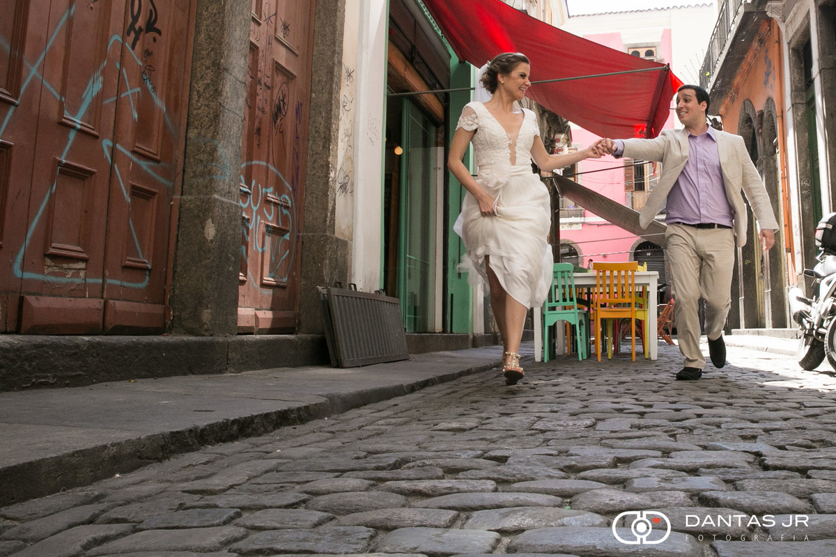 casal de noivos correndo felizes em ensaio trash the dress pelas ruas do centro histórico do Rio de Janeiro