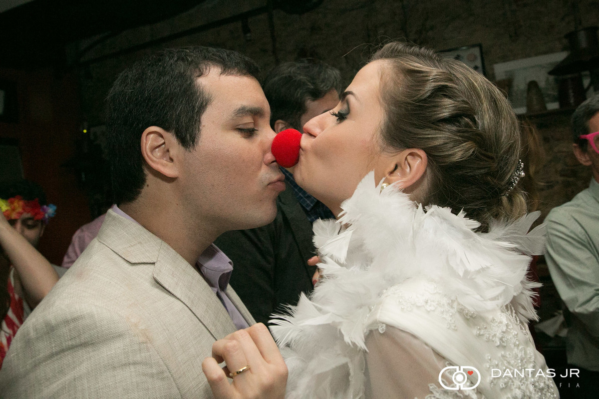 noiva beijando nariz de palhaço do noivo durante festa de casamento