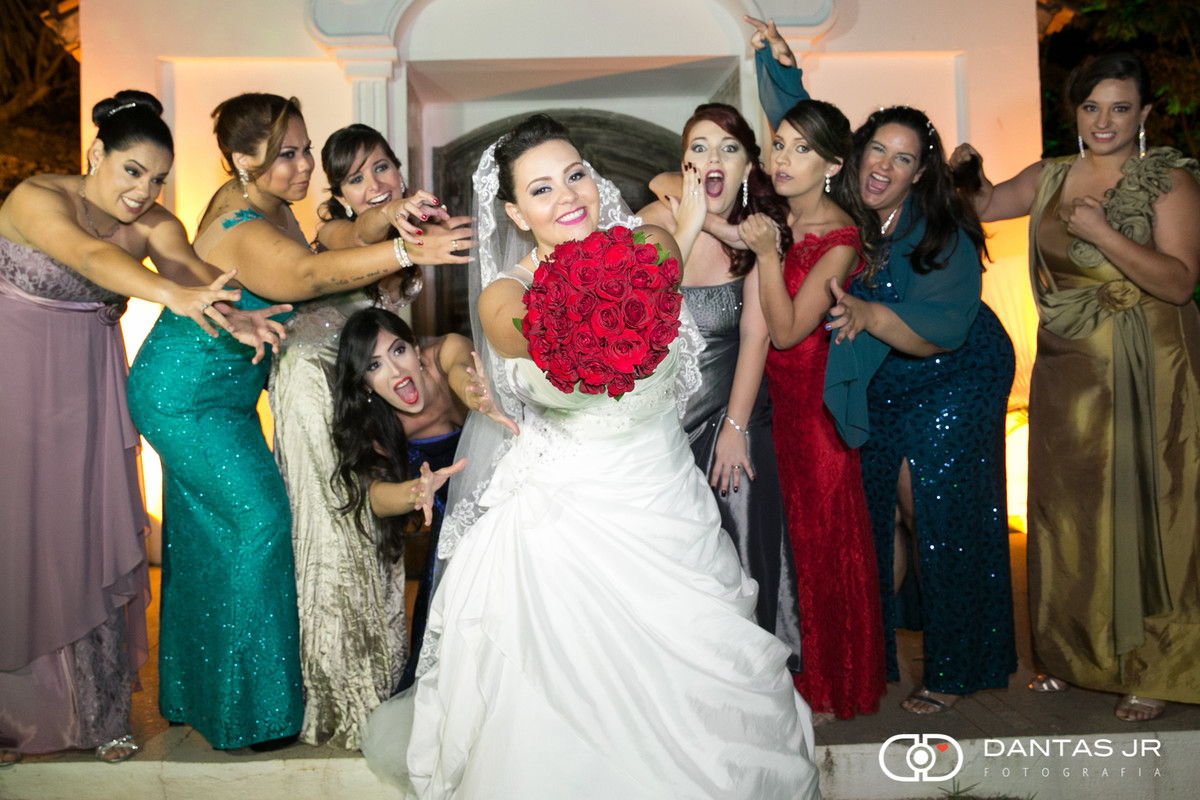 noiva mostrando buque de casamento vermelho e madrinhas disputando