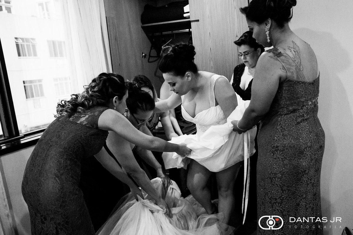noiva se vestindo com madrinhas segurando o vestido e anágua durante o making of