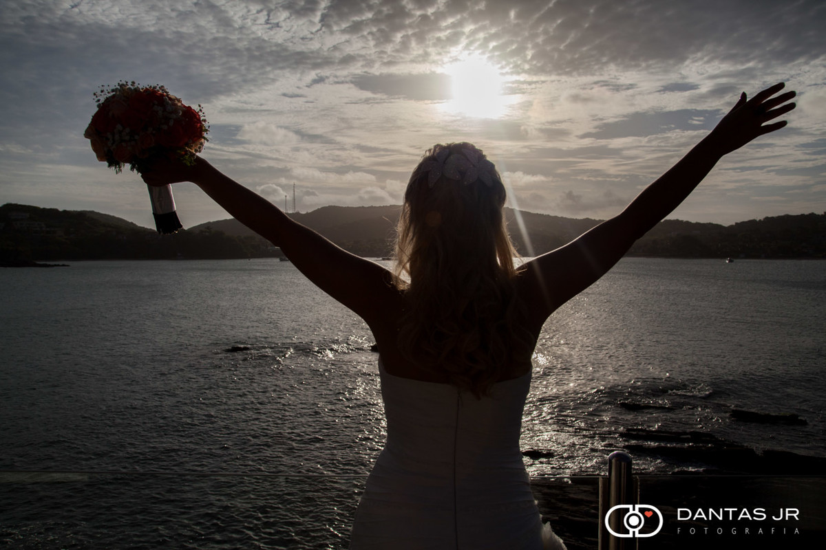 noiva abrindo os braços para o por do sol em praia de Geribá em Búzios