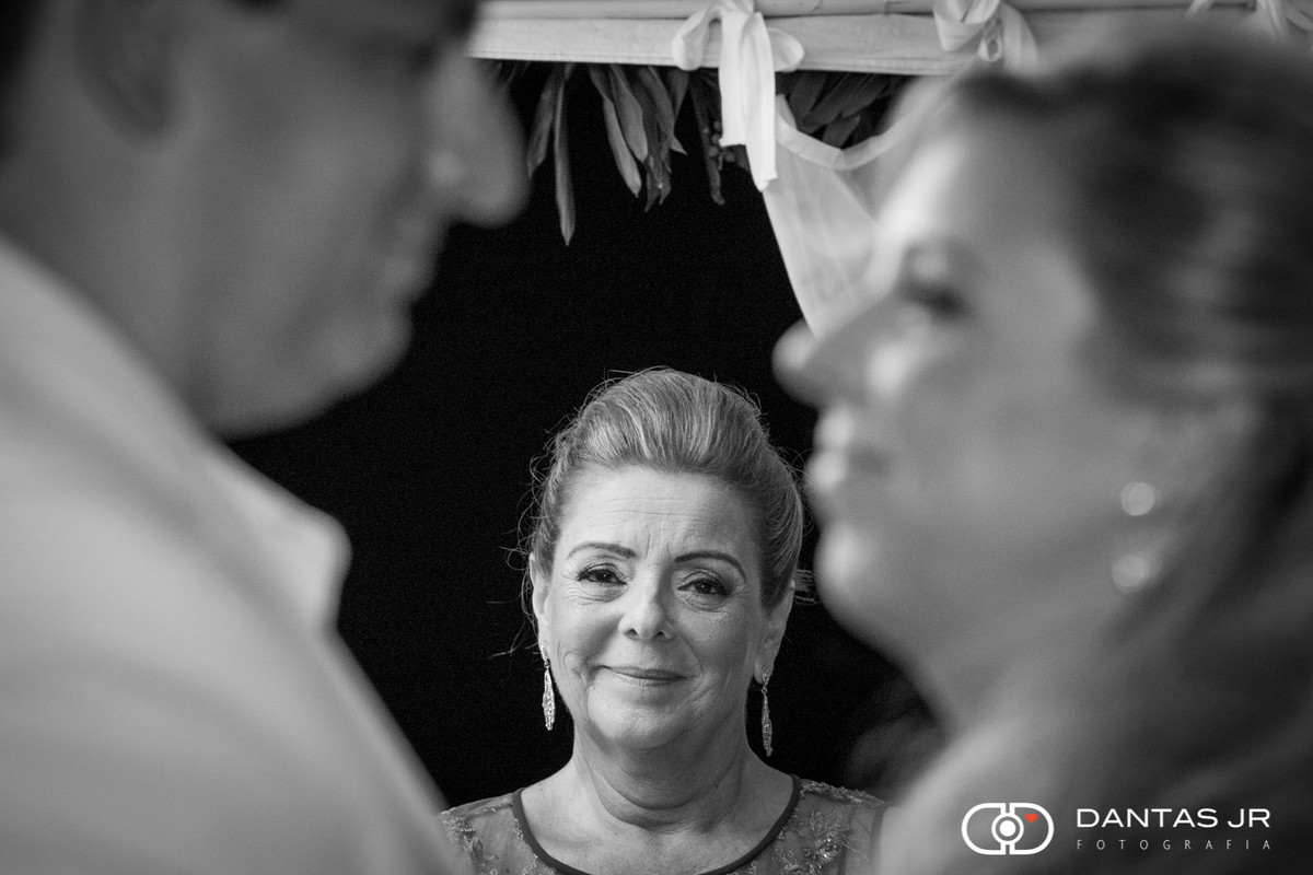 Noivos se olhando na cerimônia com mãe da noiva observando apaixonada em cerimônia na Pousada Yucas em Buzios