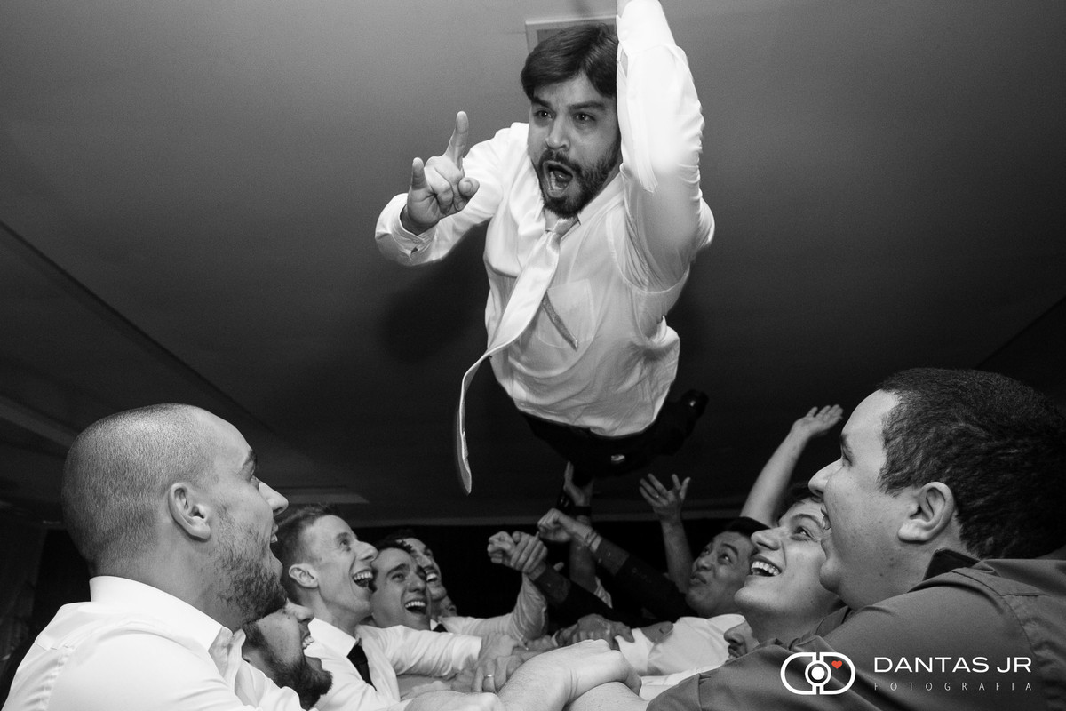 Noivo pulando sobre convidados dando mosh e fazendo sinal de rock n roll em festa de casamento no Iate Clube de Icaraí em Niteroi clicado pelo fotografo Dantas Jr.