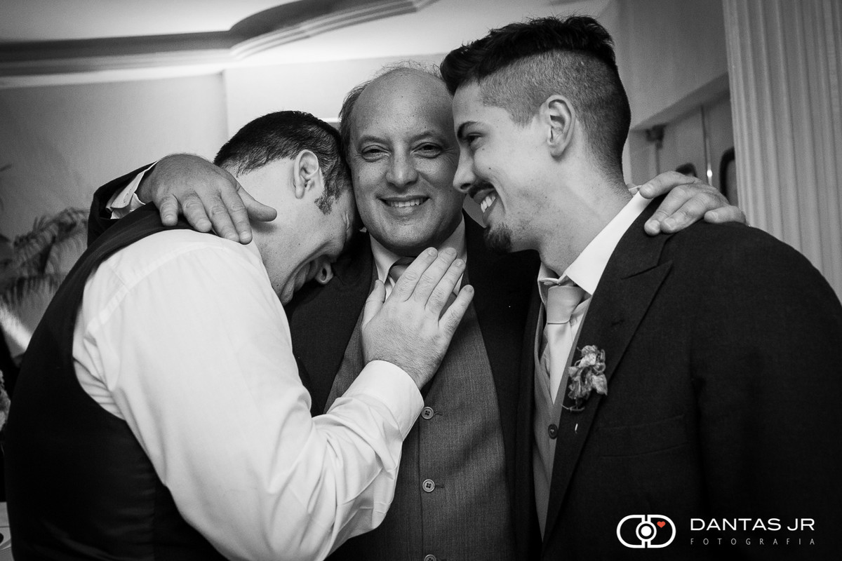 Pai da noiva com filho e noivo abraçados em festa de casamento