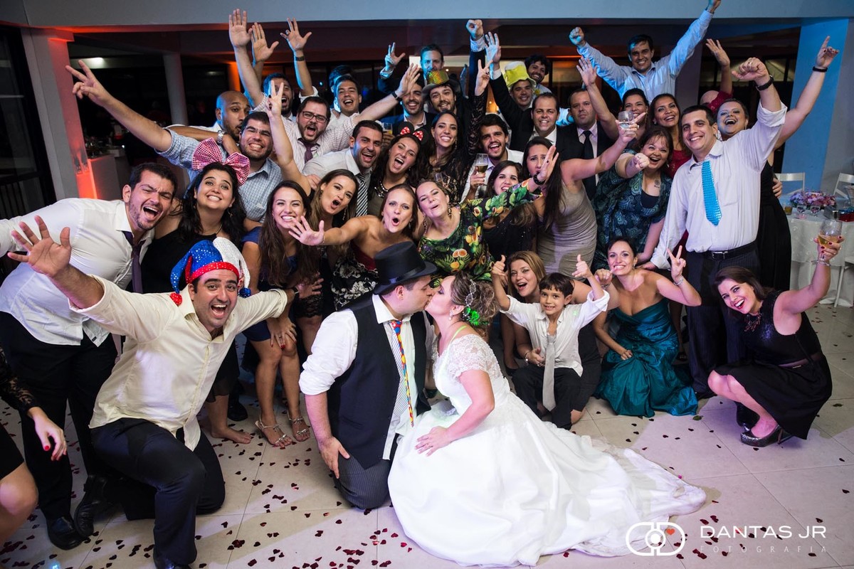 noivos se beijando com convidados vibrando ao fundo