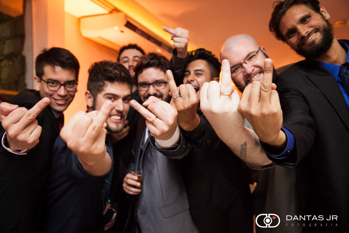 noivo e convidados mostrando o dedo anelar e uma pessoa mostrando o dedo médio