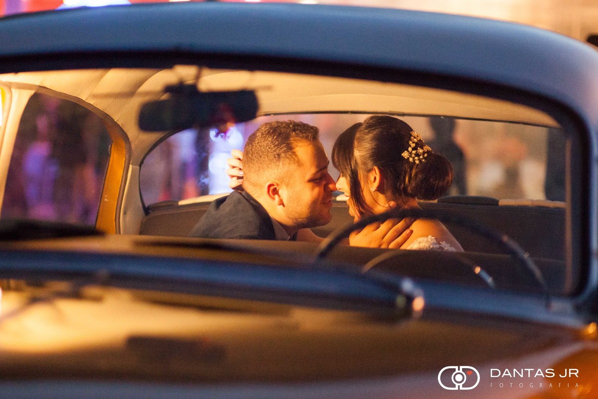 casal de noivos apaixonado se beijando dentro de carro antigo