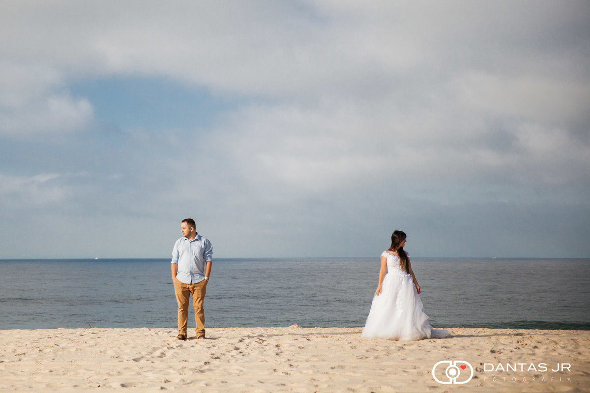 casal na praia em Trash the Dress cada um olhando pra um lado