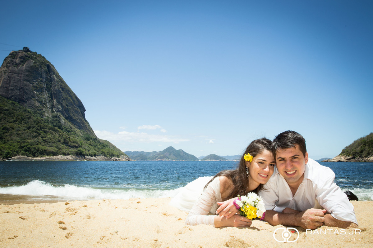 noivos deitados na areia com flores amarelas em trash the dress na praia