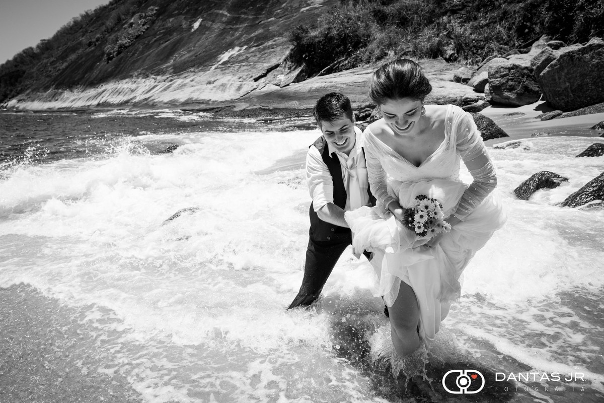 noivos andando na água em trash the dres na praia