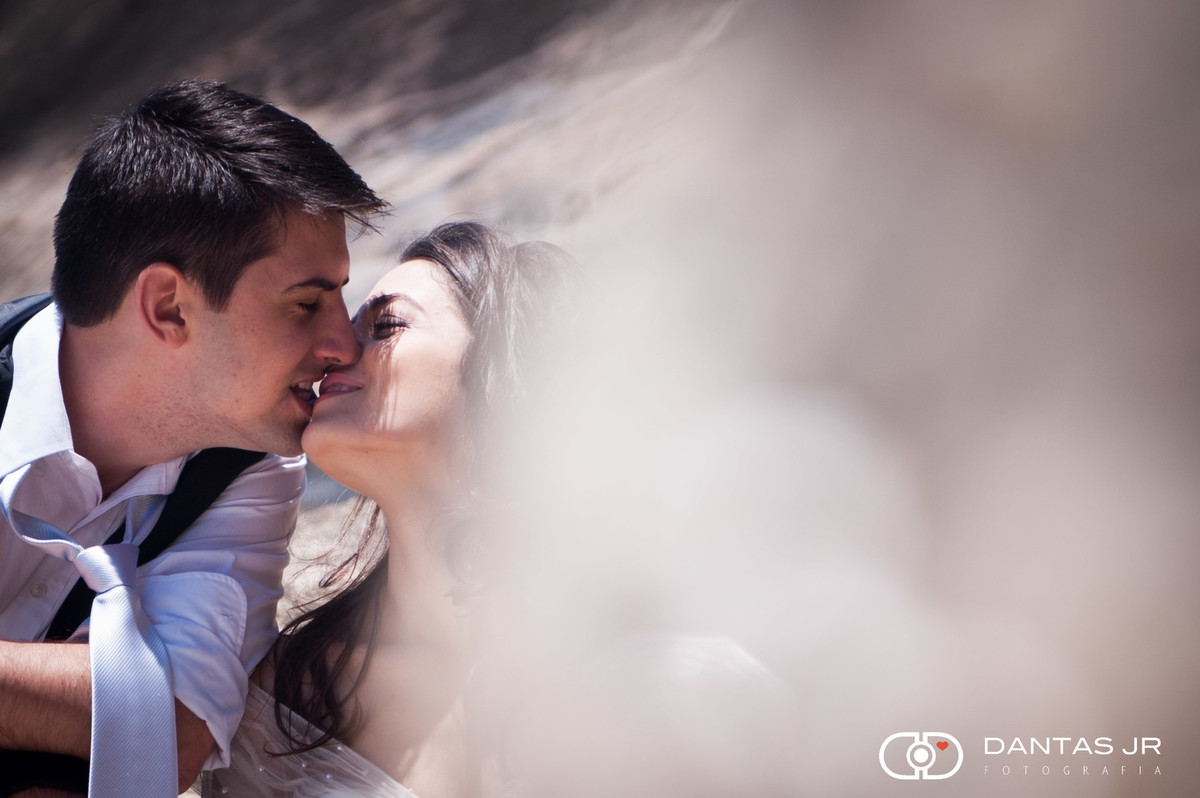 noivos se beijando observados em pedra em trash the dress na praia
