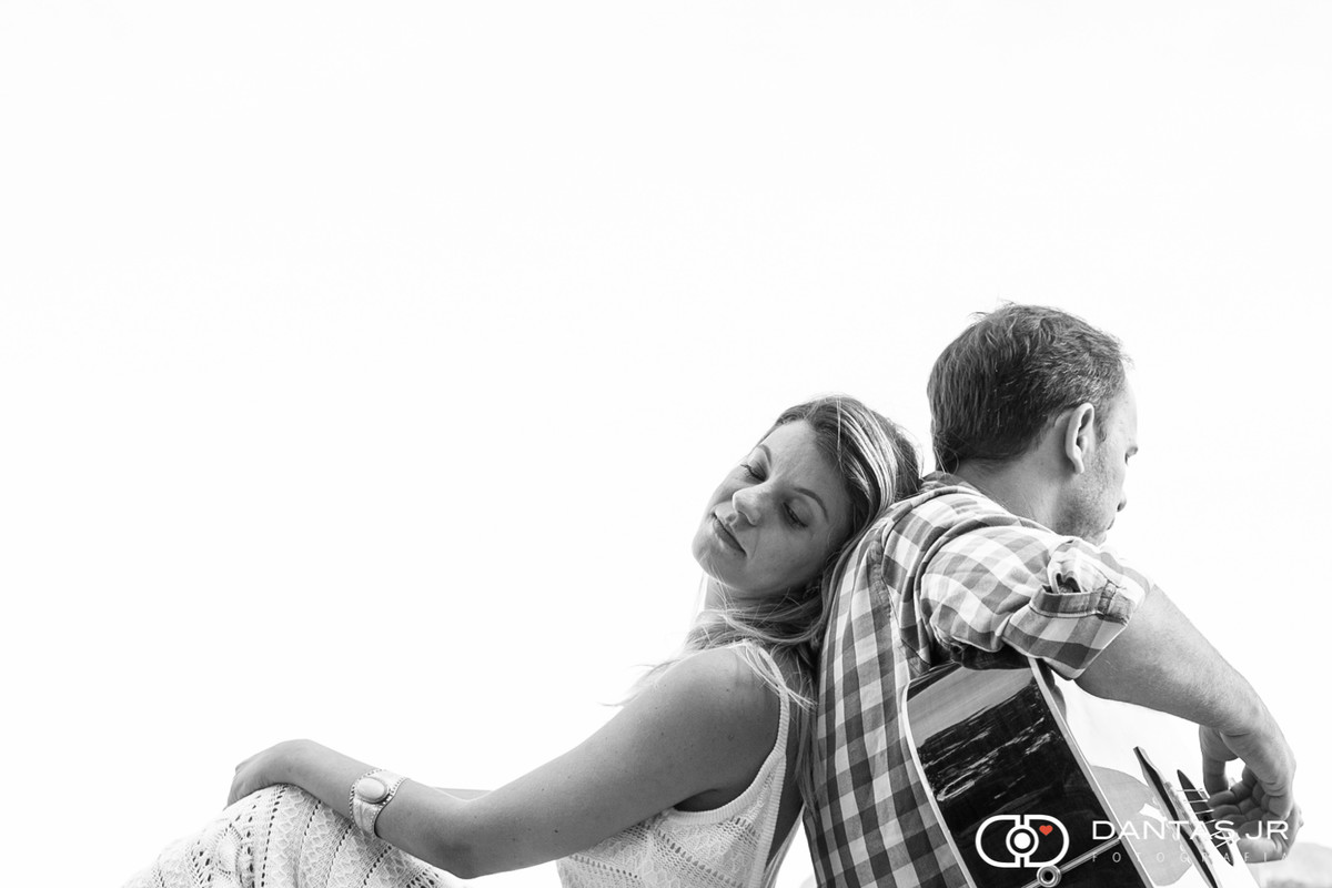 casal romantico com ele tocando violão e ela deitada nas costas dele