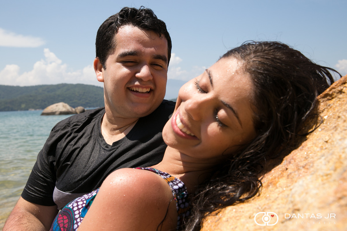 namorado olhando namorada de olhos fechados encostada em pedra na praia de ilha grande
