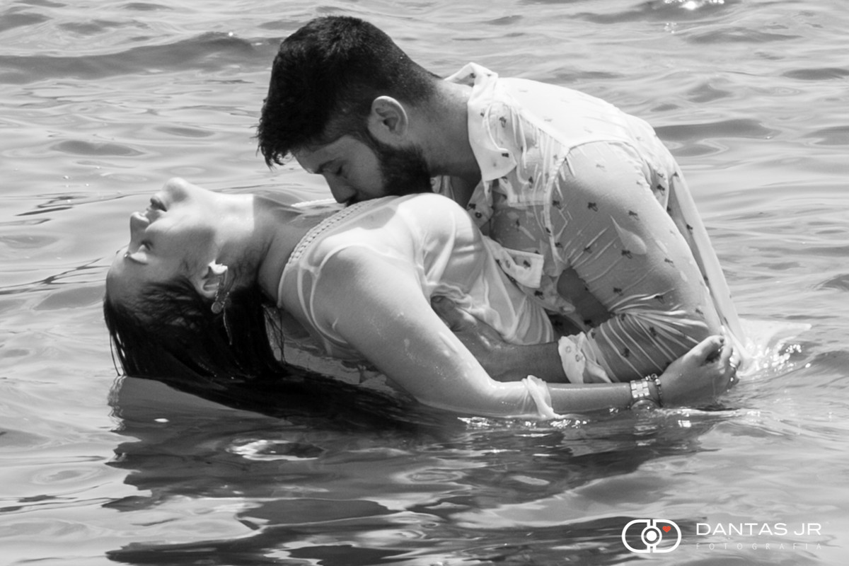 noivo beijando colo da noiva de maneira sensual dentro da água em praia no ensaio pre wedding