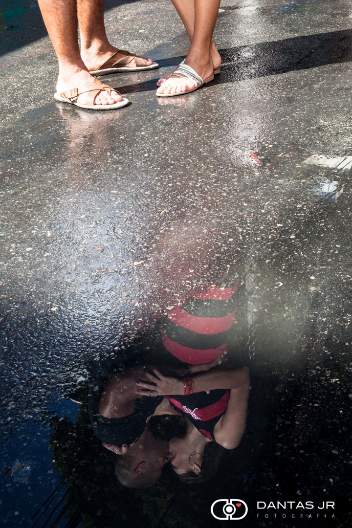casal com roupas do flamengo se beijando e refletidos na poça de água no chão