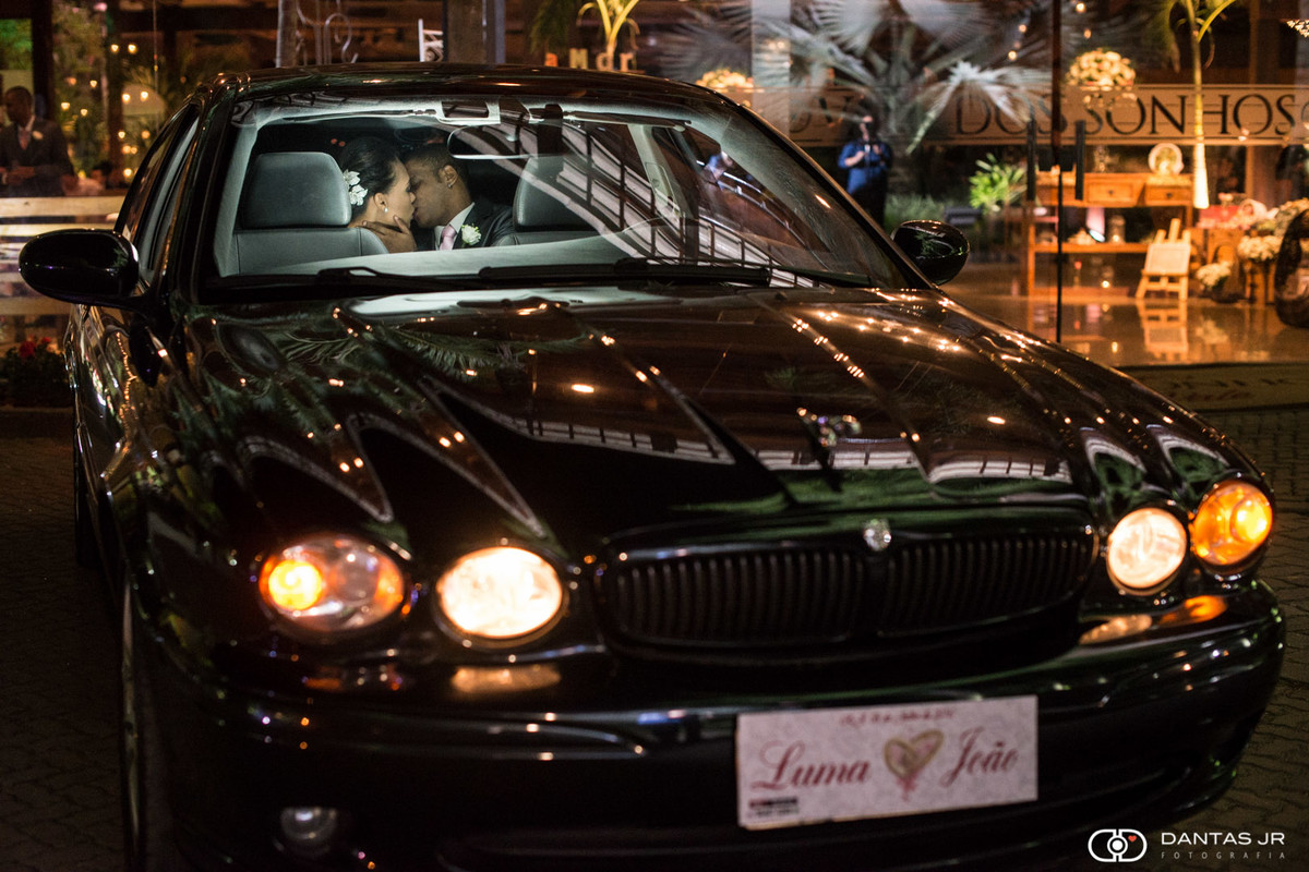 noivos se beijando dentro de Jaguar preto após a cerimônia